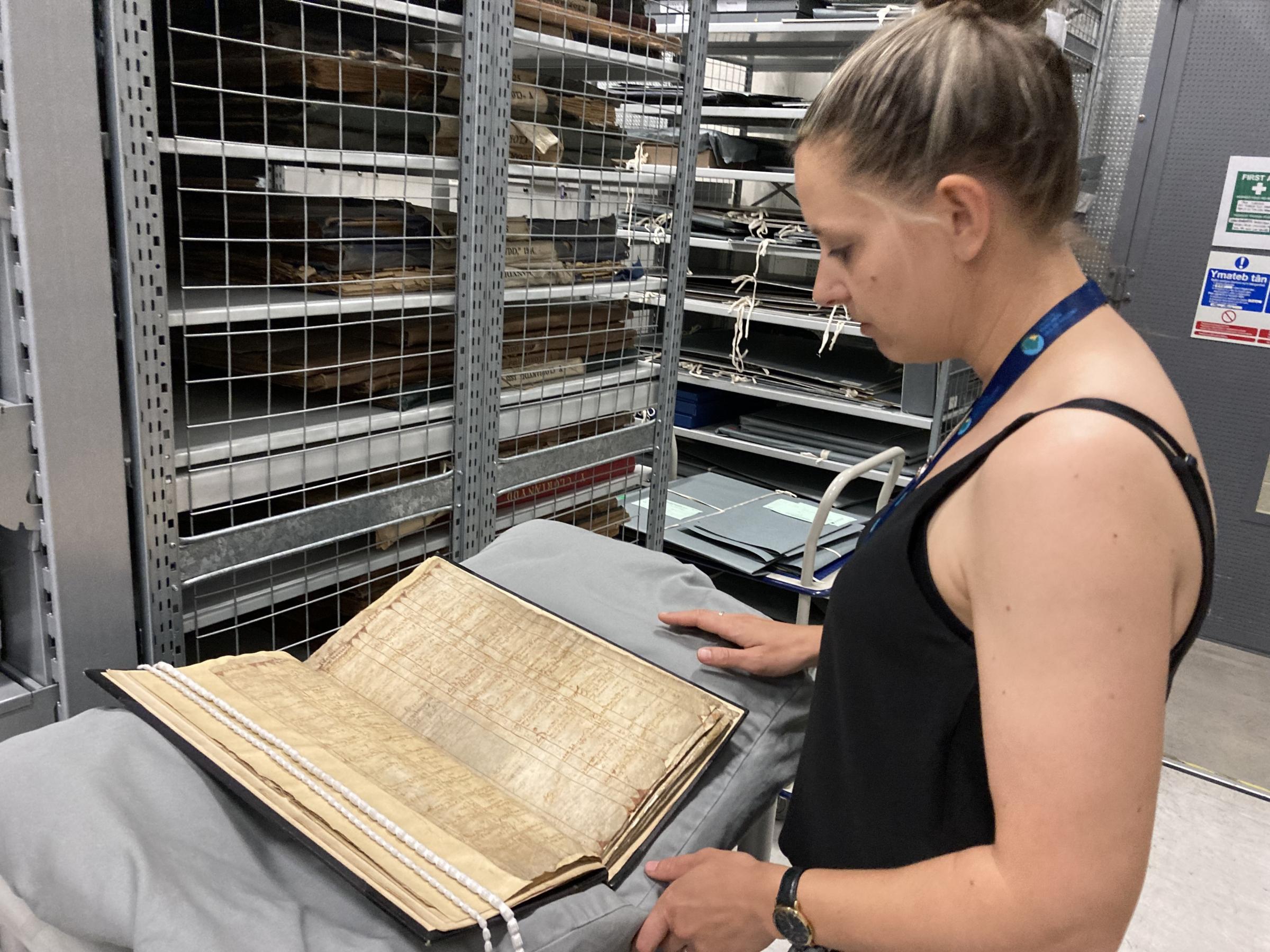 Kelly Parry at the Anglesey County Council Archives inspects the Penrhoslligwy parish register which dates from 1578 - 1766 and chronicle births, marriages and deaths. Picture: Dale Spridgeon