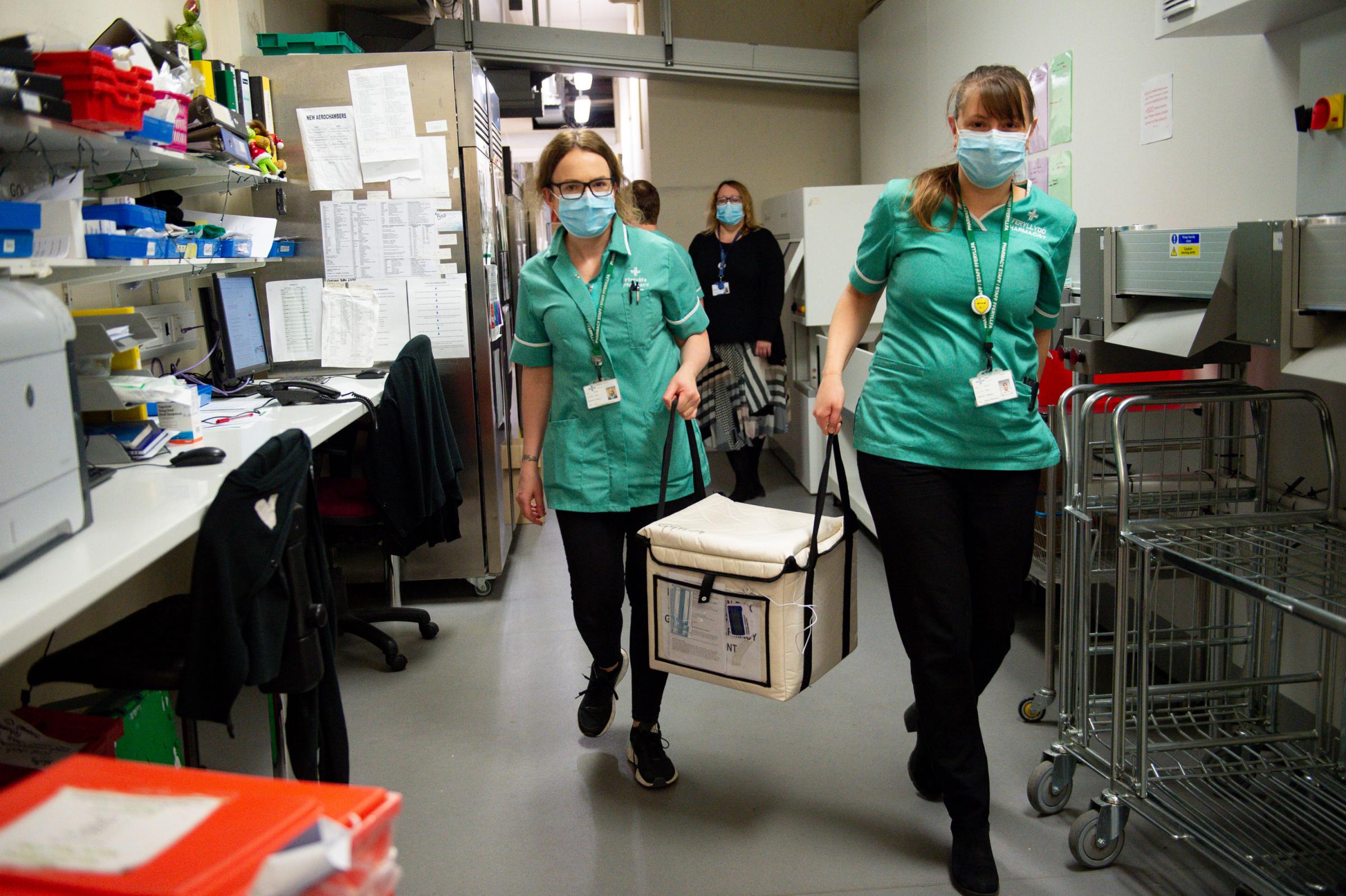 Pharmacists transport a cooler containing the Moderna vaccine, at the West Wales General Hospital in Carmarthen, the third vaccine to be approved for use in the UK, which is to be given to patients in Wales from Wednesday. Picture date: Wednesday April