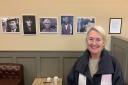 Siân Gwenllian next to Garry Stuart’s photos, which are displayed at Bwyd Da Bangor