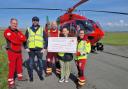 Lucy and Simon present a cheque at the air ambulance base in Caernarfon