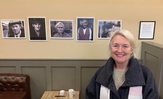 Siân Gwenllian next to Garry Stuart’s photos, which are displayed at Bwyd Da Bangor