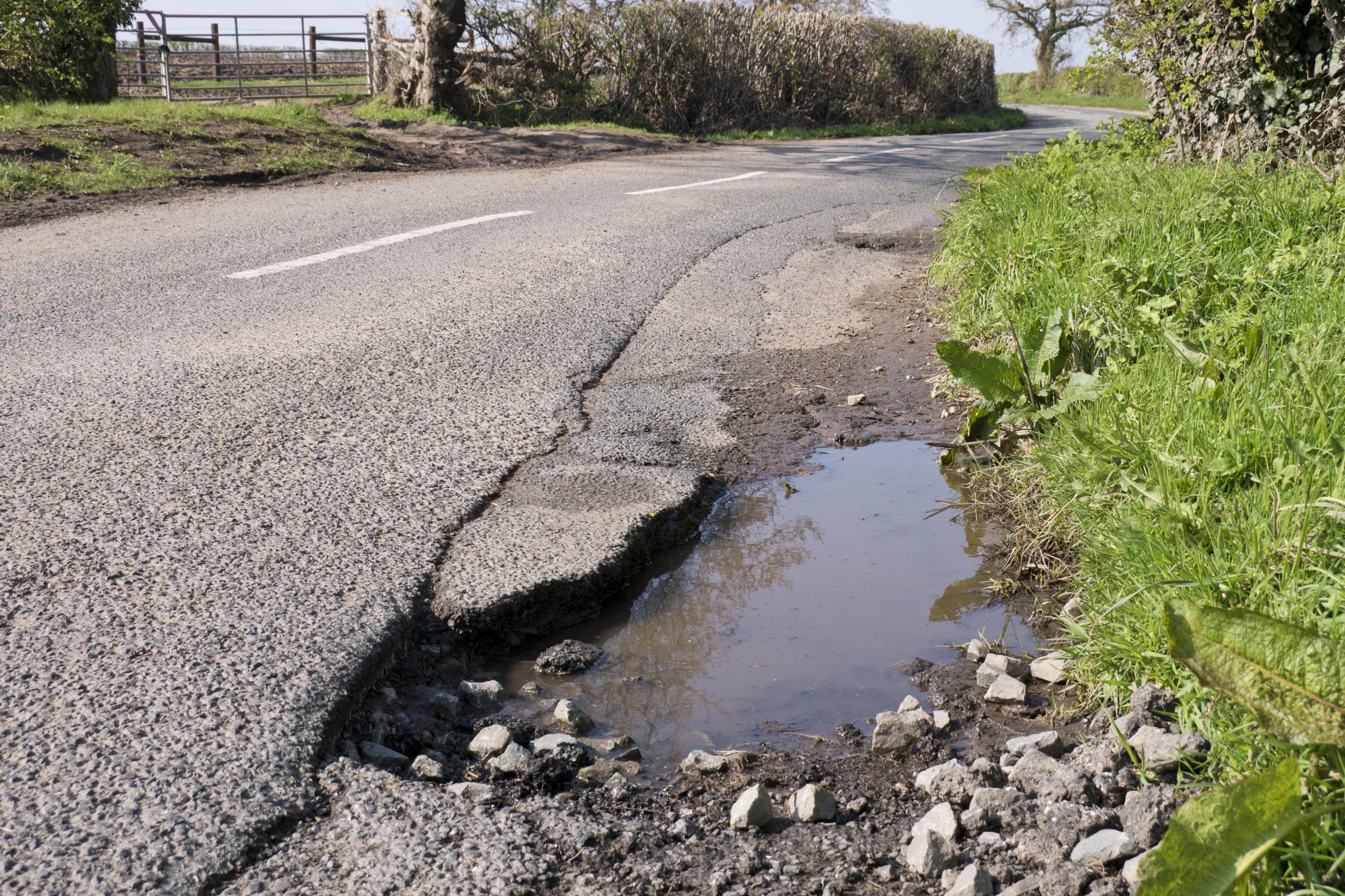 Unrepaired pothole - surface damage to surface on a rural road.