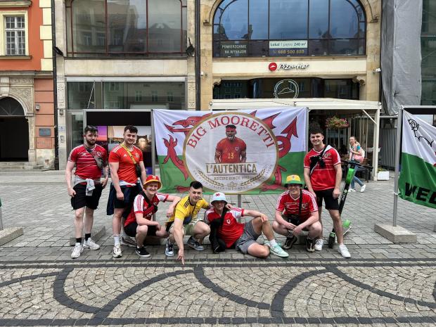 North Wales Chronicle: Wales superfan Cai Jones and friends with their popular 'Big Mooretti' flag. Photo: Cai Jones