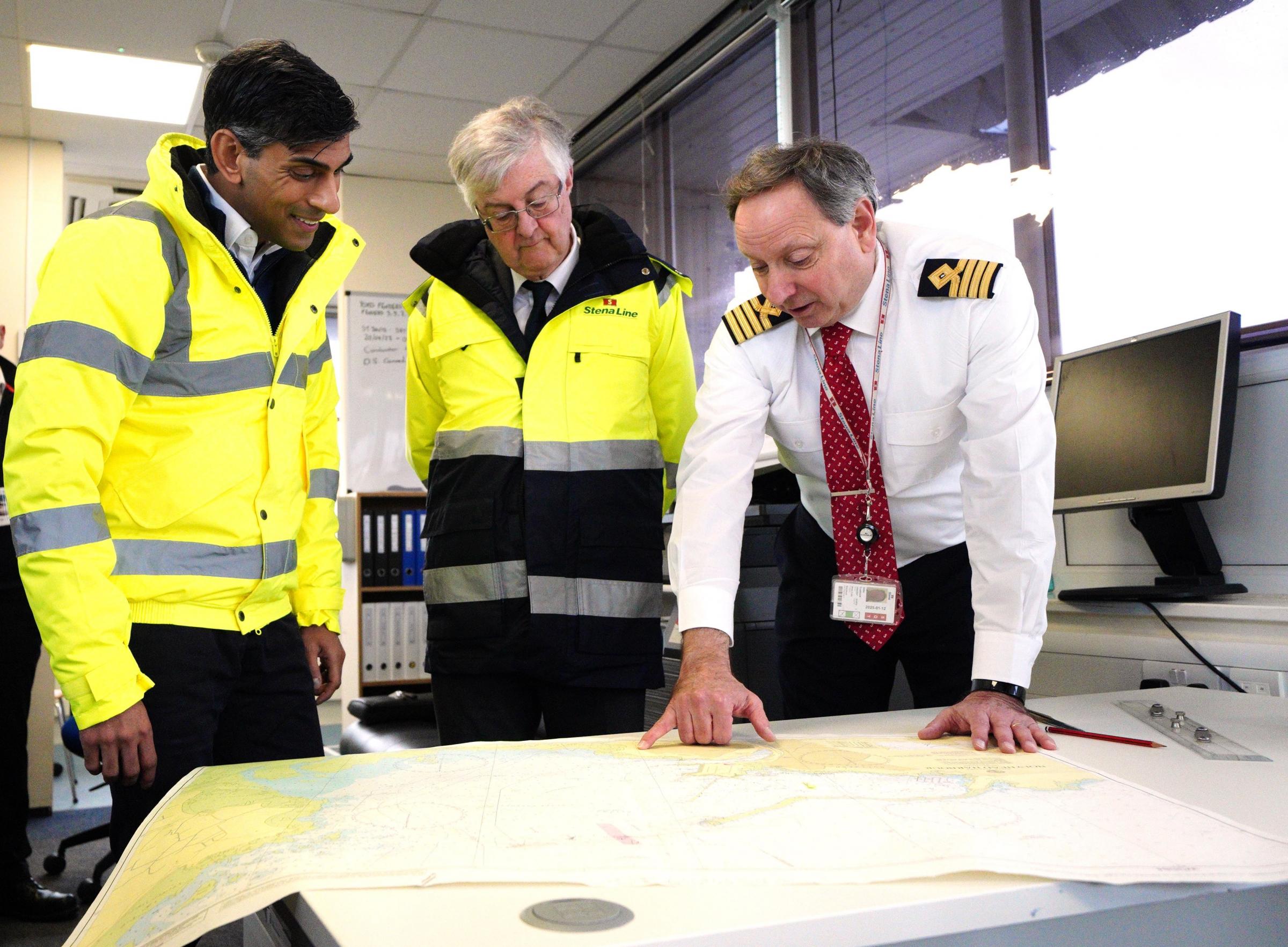 (left to right) Prime Minister Rishi Sunak and First Minister of Wales Mark Drakeford with John Goddard harbour master looking at charts during a visit to the Port of Holyhead in Anglesey, North Wales, for the announcement of the creation of two