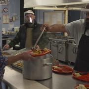 Chris Summers, one of the founders of Porthi Pawb, and Chris Roberts, star of S4C’s Bwyd Epic Chris, serving a meal to one of the charity’s volunteers after a long shift.