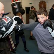 Police and Community Trust chair Ashley Rogers helps out on the pads/heavy bag for young southpaw Arron Jones.