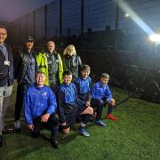 L-R: Police and Crime Commissioner Andy Dunbobbin, Bangor Saints Coaching Coordinator Daf Roberts, North Wales Police PCSO David Griffiths and Gwynedd High Sheriff Janet Phillips with players of the Bangor Saints U13 football team.